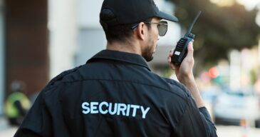 Radio, man and a security guard or safety officer outdoor on a city road for communication. Back of a person with a walkie talkie on urban street to report crime for investigation and surveillance.